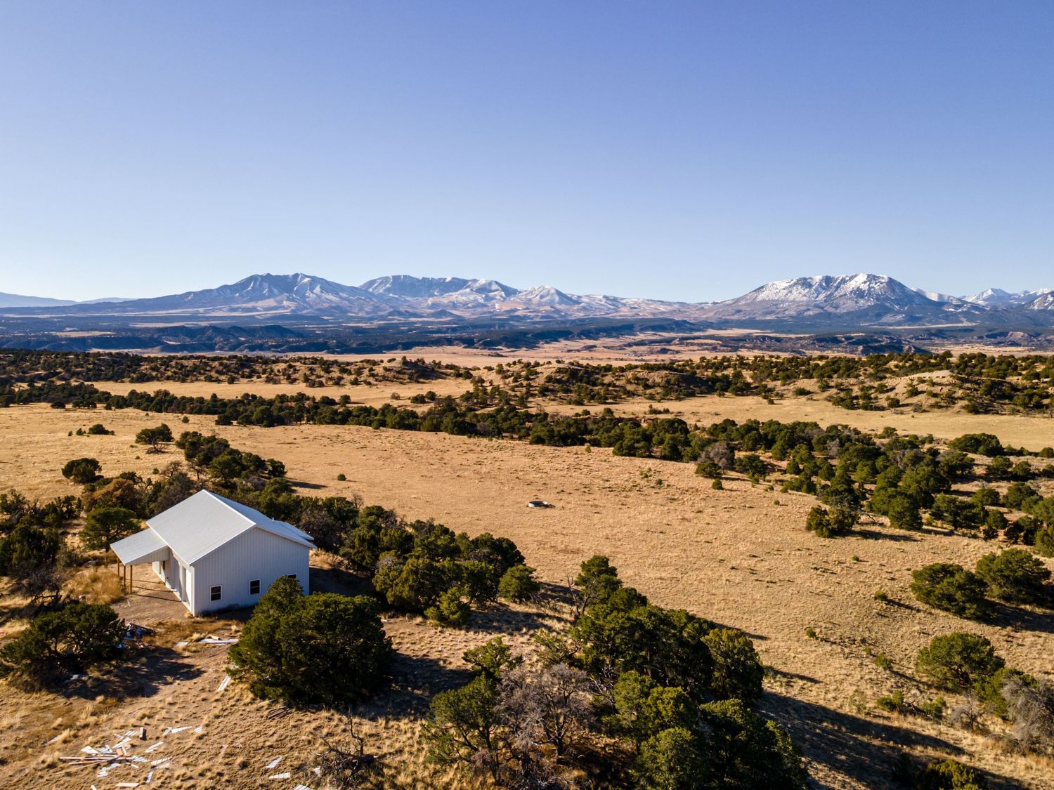 Aerial view of white building surrounded by desert terrain with mountain range in distance.