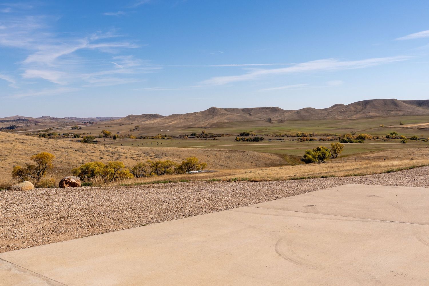 Panoramic view of rolling hills and vast open plains under a blue sky in an arid western landscape.