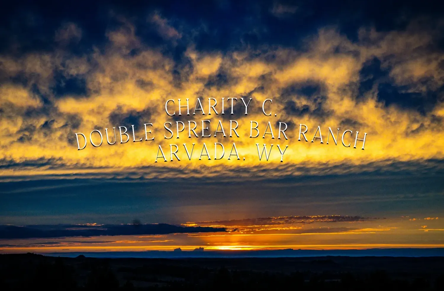 Dramatic sunset sky with vibrant orange clouds stretching across the horizon over silhouetted mountains.