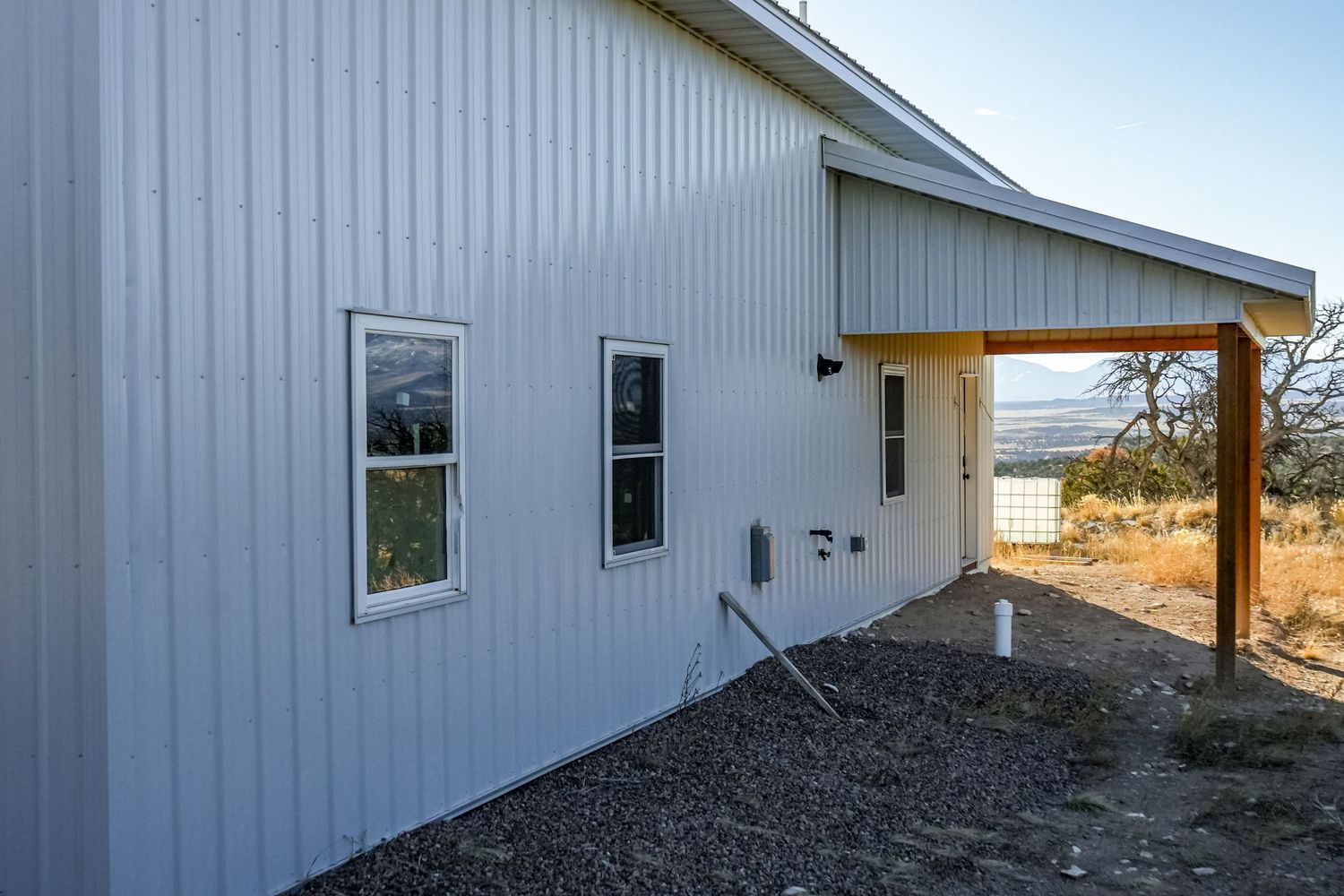 Modern white building with gravel landscaping against desert mountain backdrop.