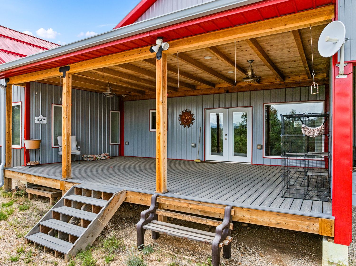 Covered front porch with wood deck, ceiling fans, French doors, and red metal roof accents.