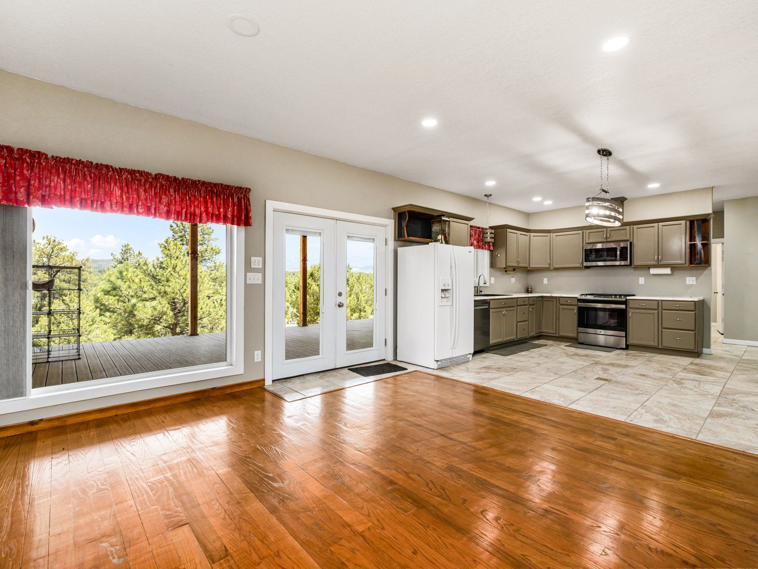 Open living area with hardwood floors, French doors, and a view of the kitchen with gray cabinetry.