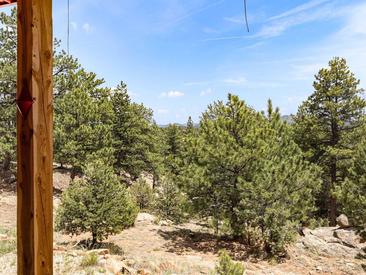 Scenic mountain view with dense pine trees and rocky terrain under a clear blue sky.