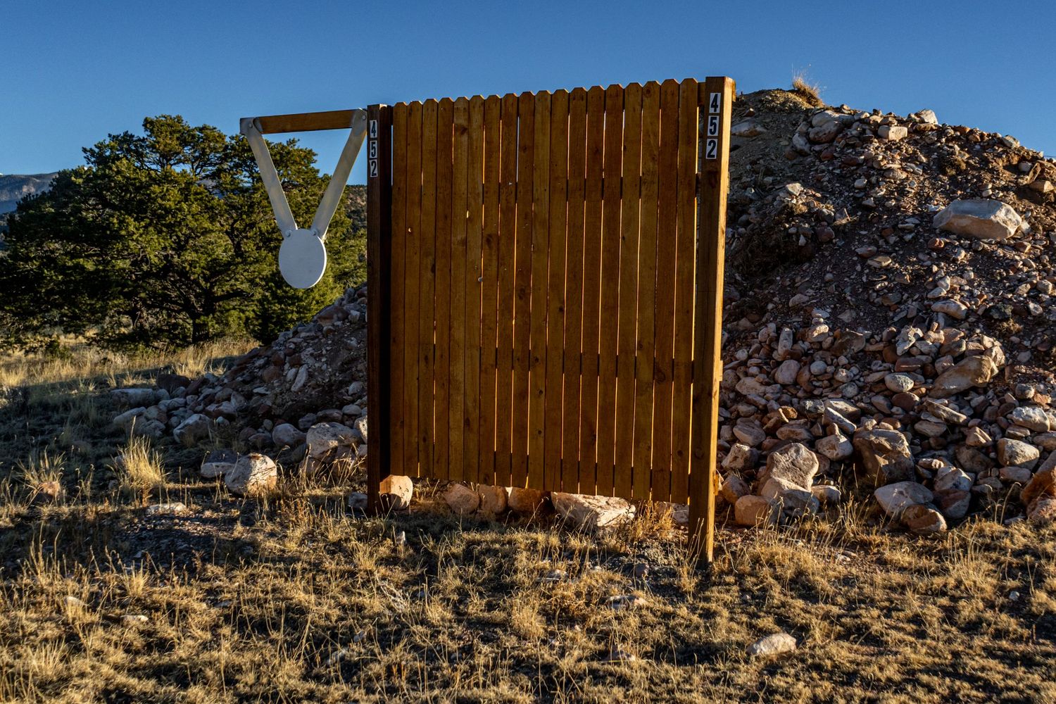 Wooden fence structure in desert landscape with rocky outcrops and mountains in background.