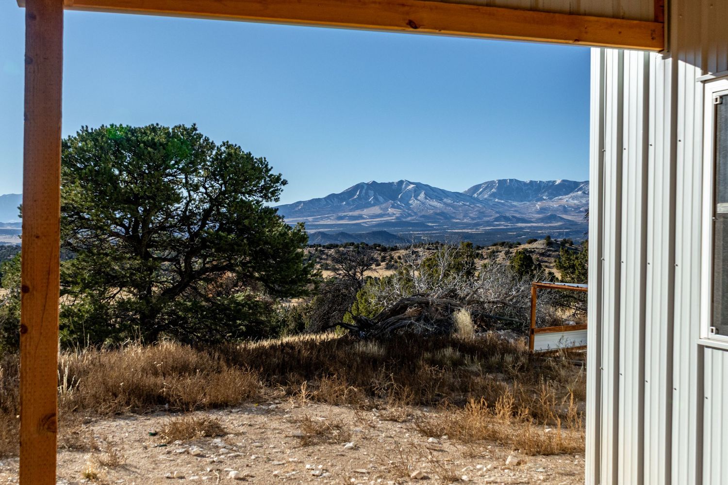 Mountain vista framed through wooden porch with desert landscape in foreground.
