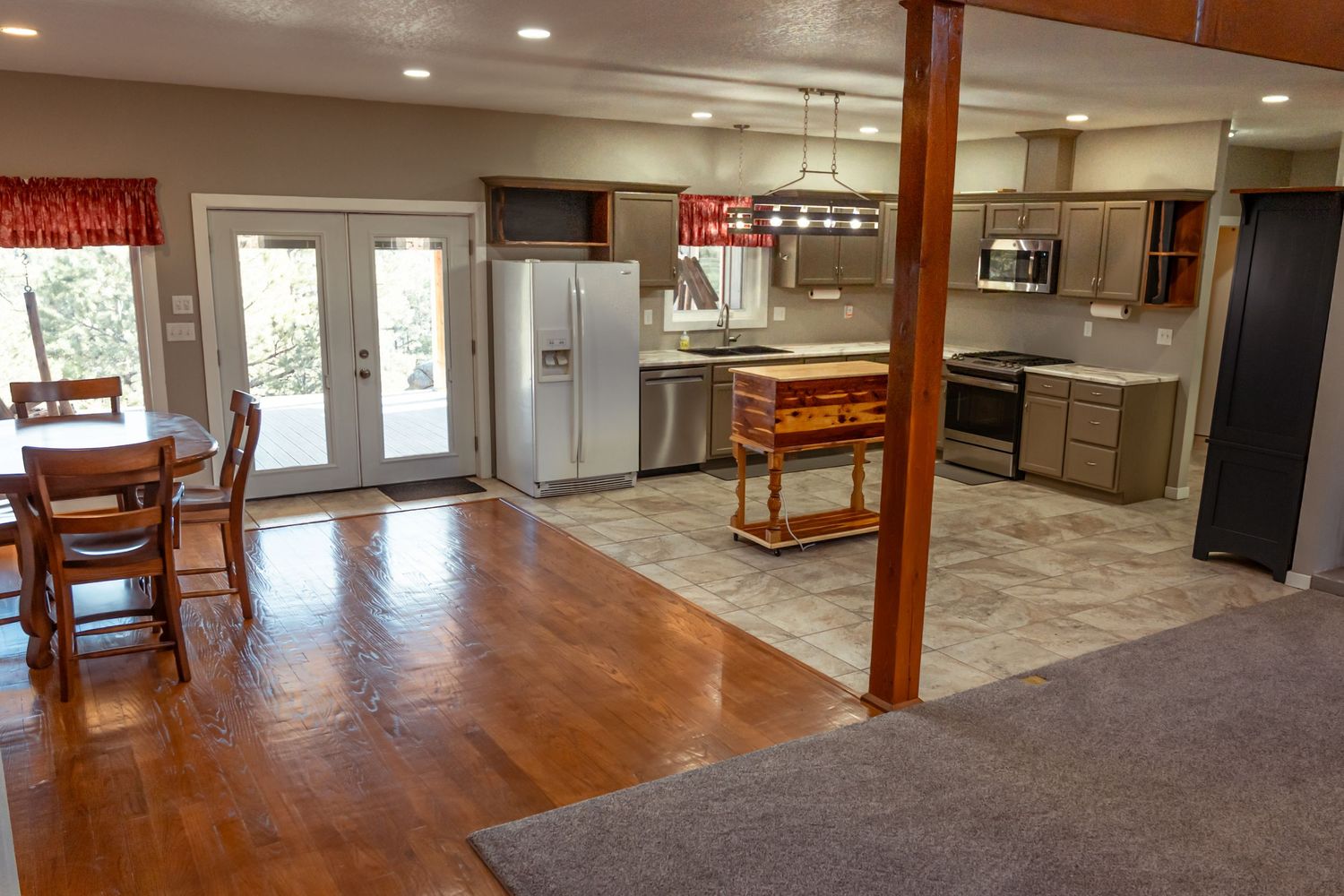 Modern open concept kitchen and dining area with hardwood floors and French doors leading to outdoor space.