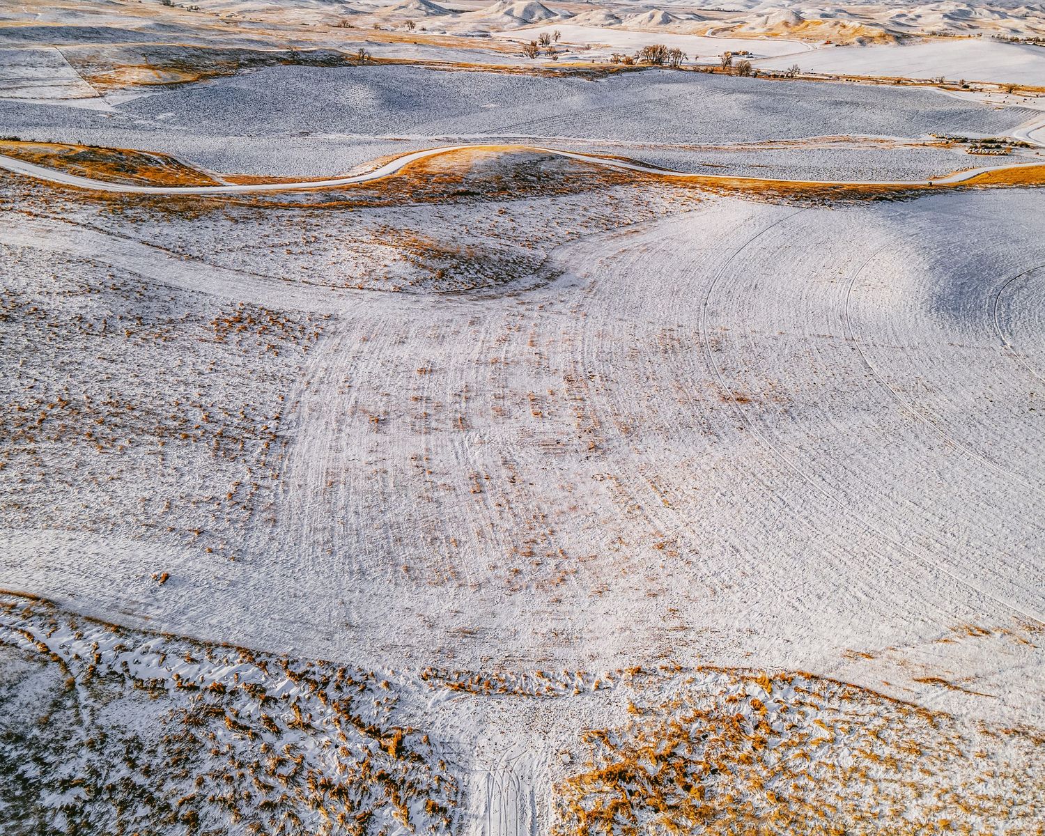 Snowy hillside terrain with winding paths and scattered vegetation visible from above.
