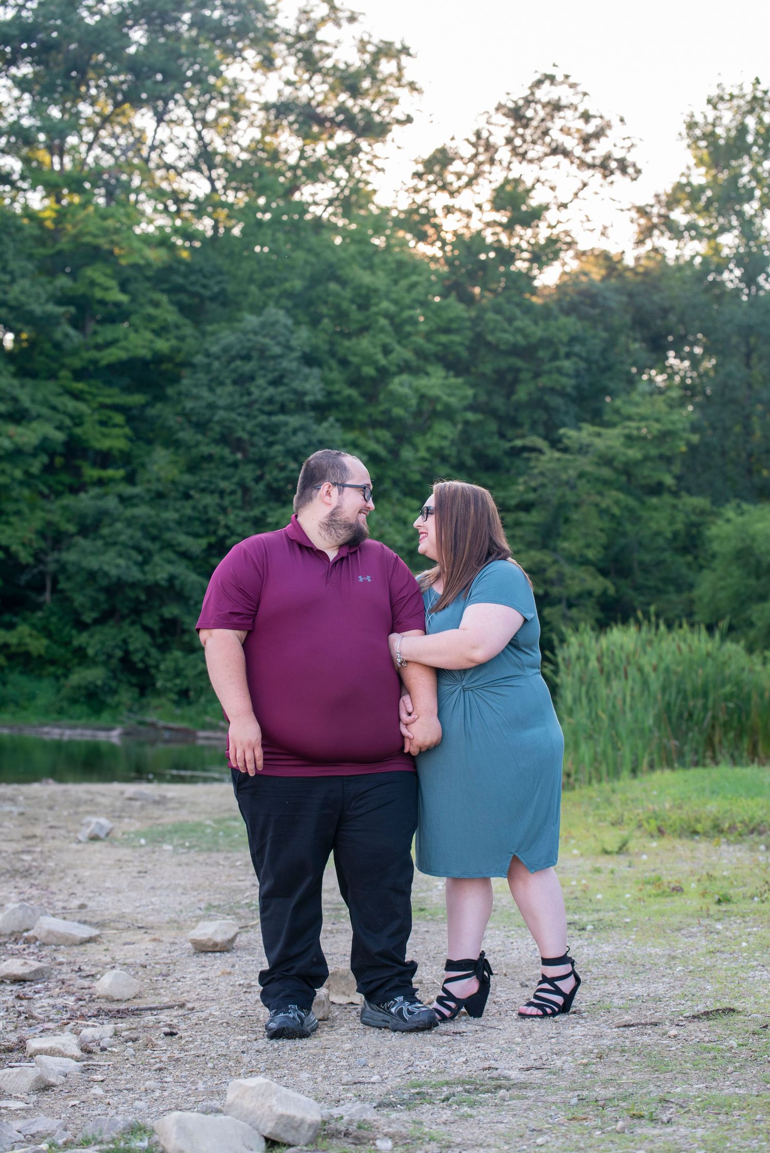 A couple sharing a romantic moment at sunset near a wooded area.