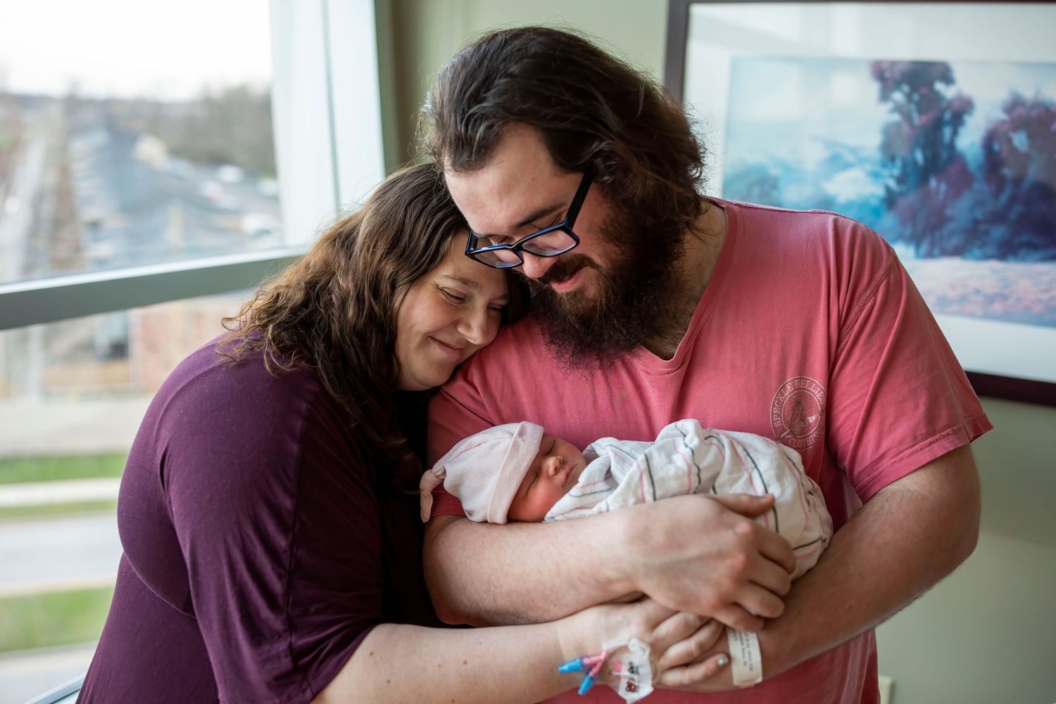 Parents share tender moment with newborn baby during indoor lifestyle session.
