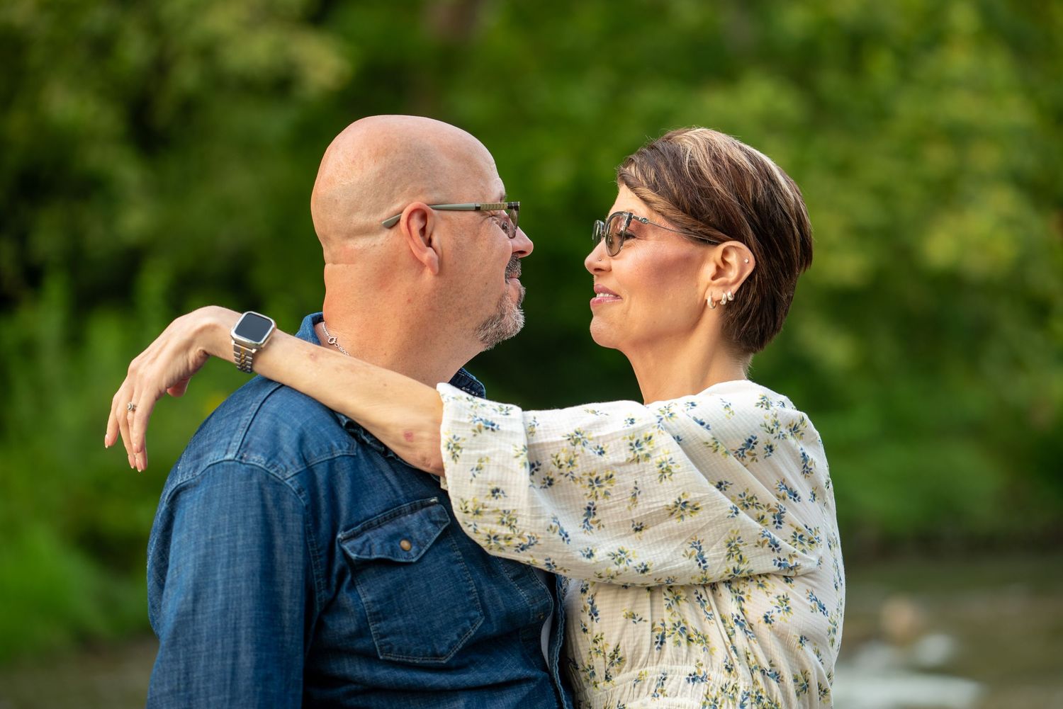 Couple embracing outdoors against green natural background.