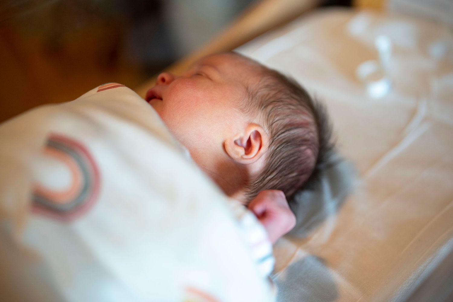 Newborn baby sleeping peacefully in a soft white blanket.