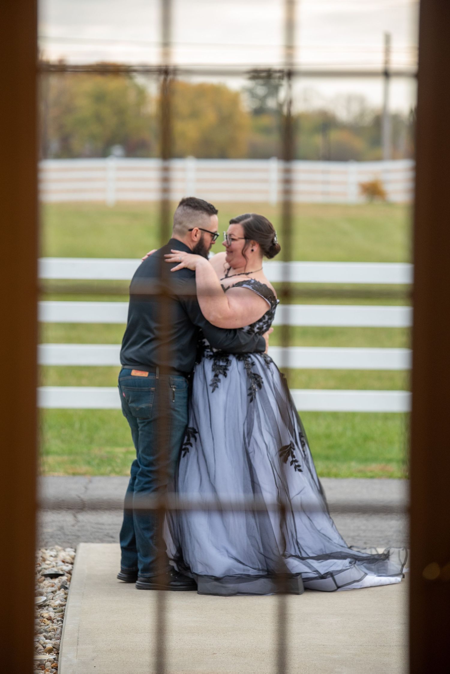Couple sharing a tender moment viewed through window frame.