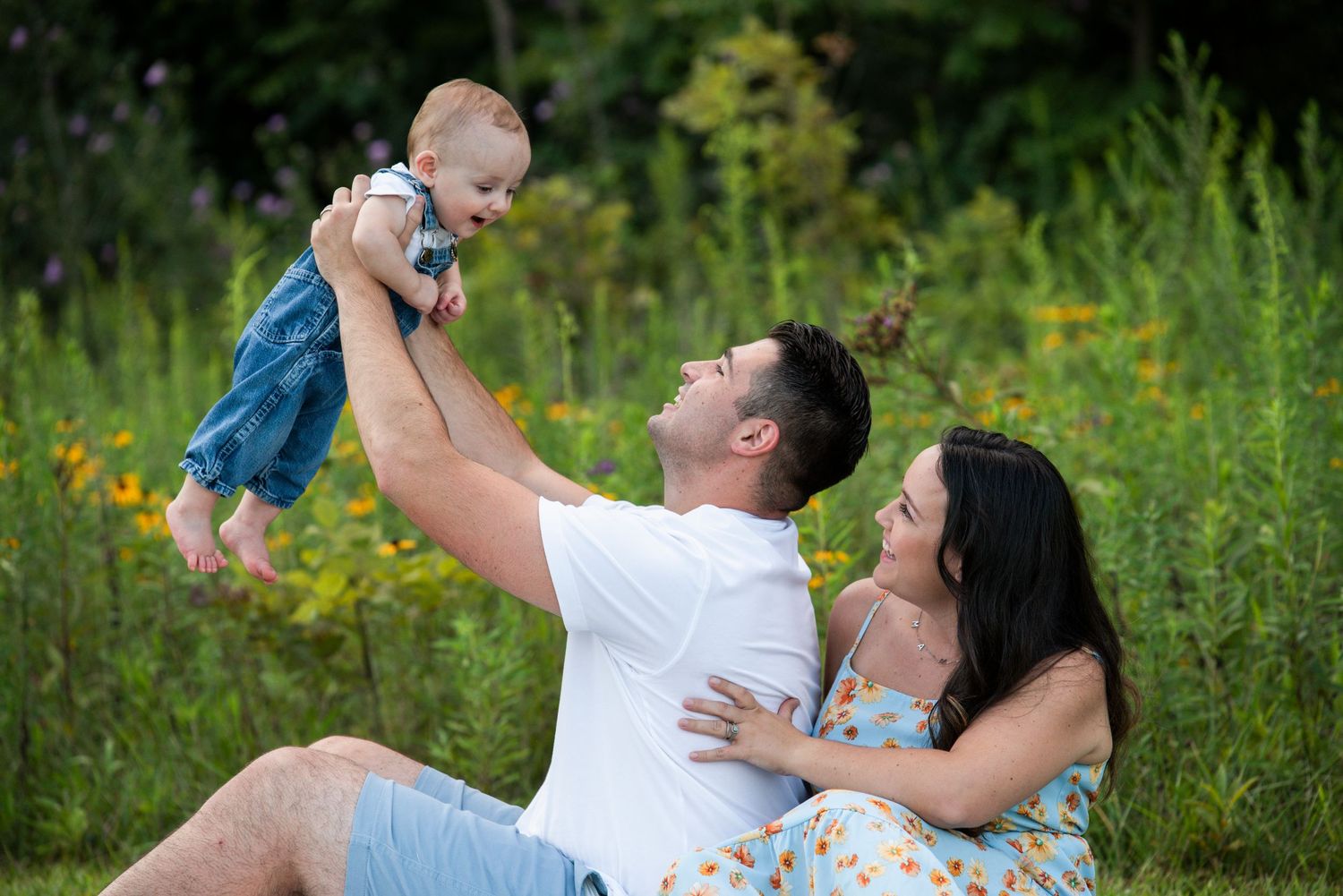 Family plays together in wildflower field during summer photo session.