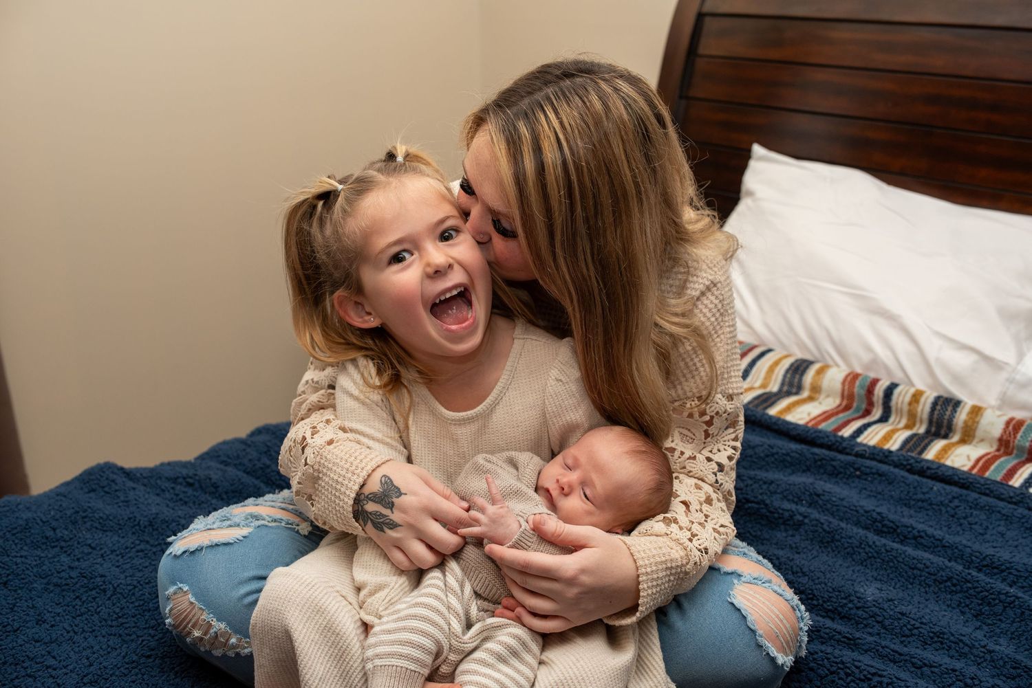 A joyful family moment captured on a blue bed with a newborn baby.