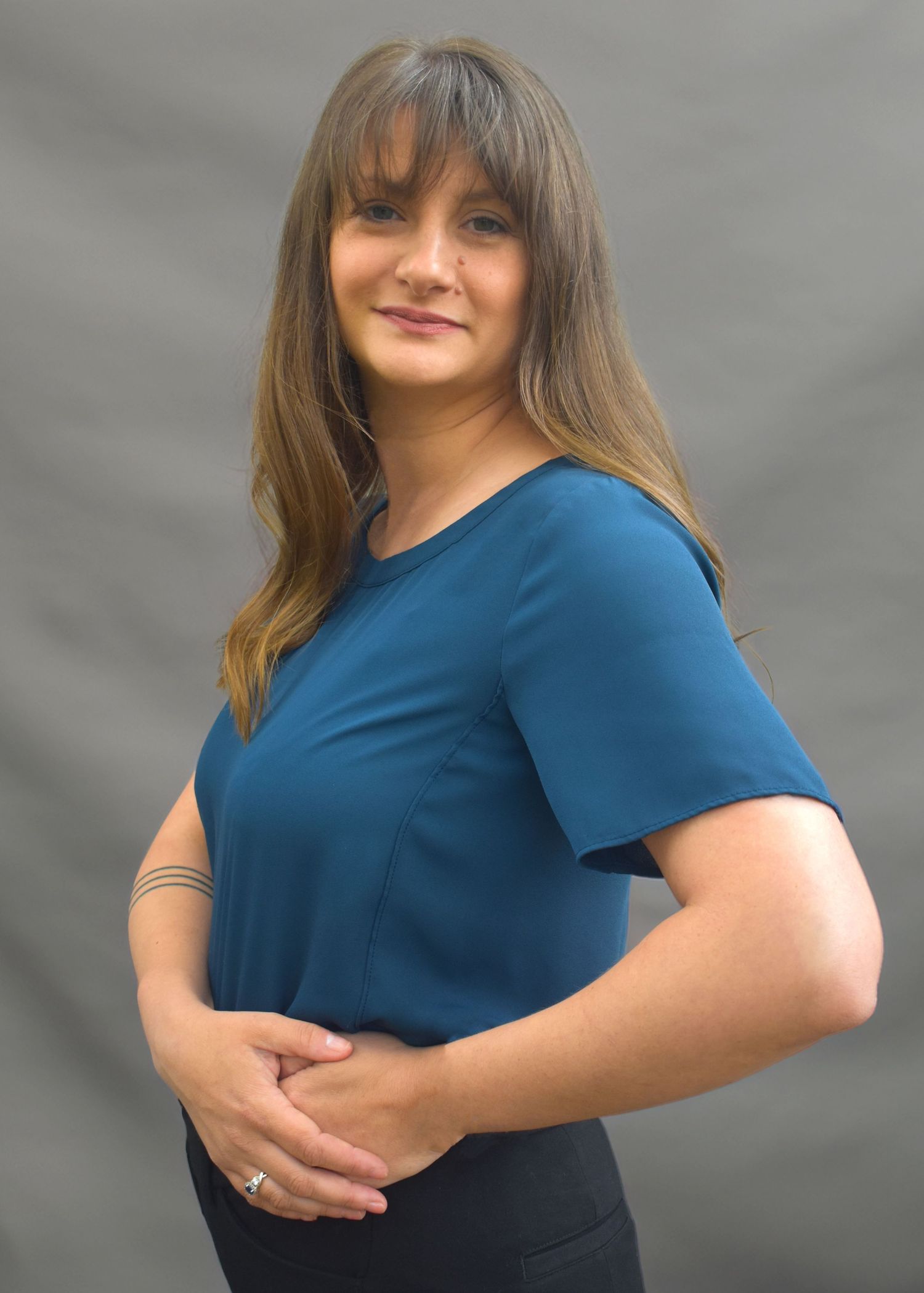 Woman in navy blue shirt poses against grey background in casual portrait series.