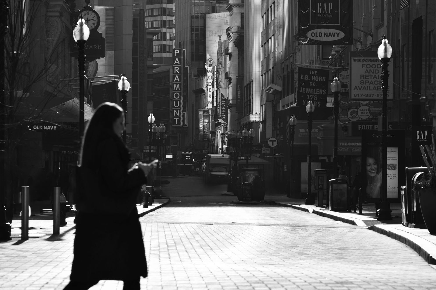 Black and white cityscape with buildings and street lamps in downtown area.