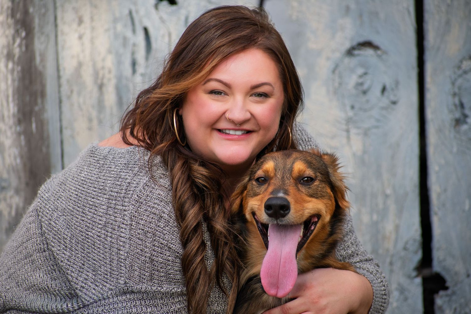 Woman cuddles with happy dog against rustic blue wooden backdrop.