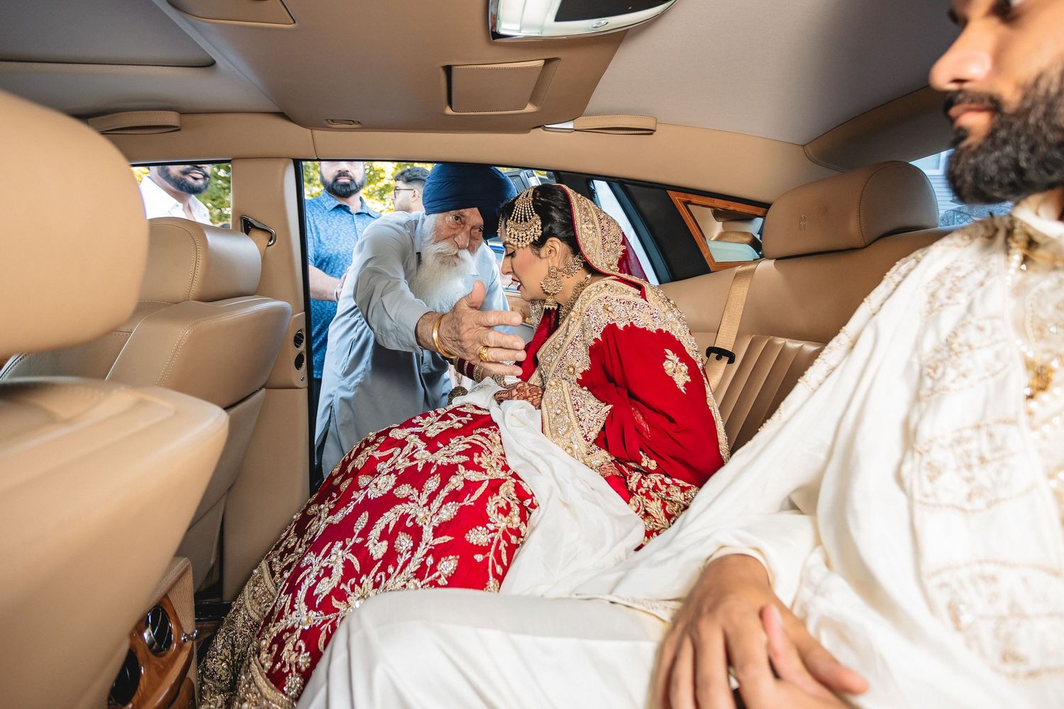 Interior view of luxury car with red and white wedding attire visible.