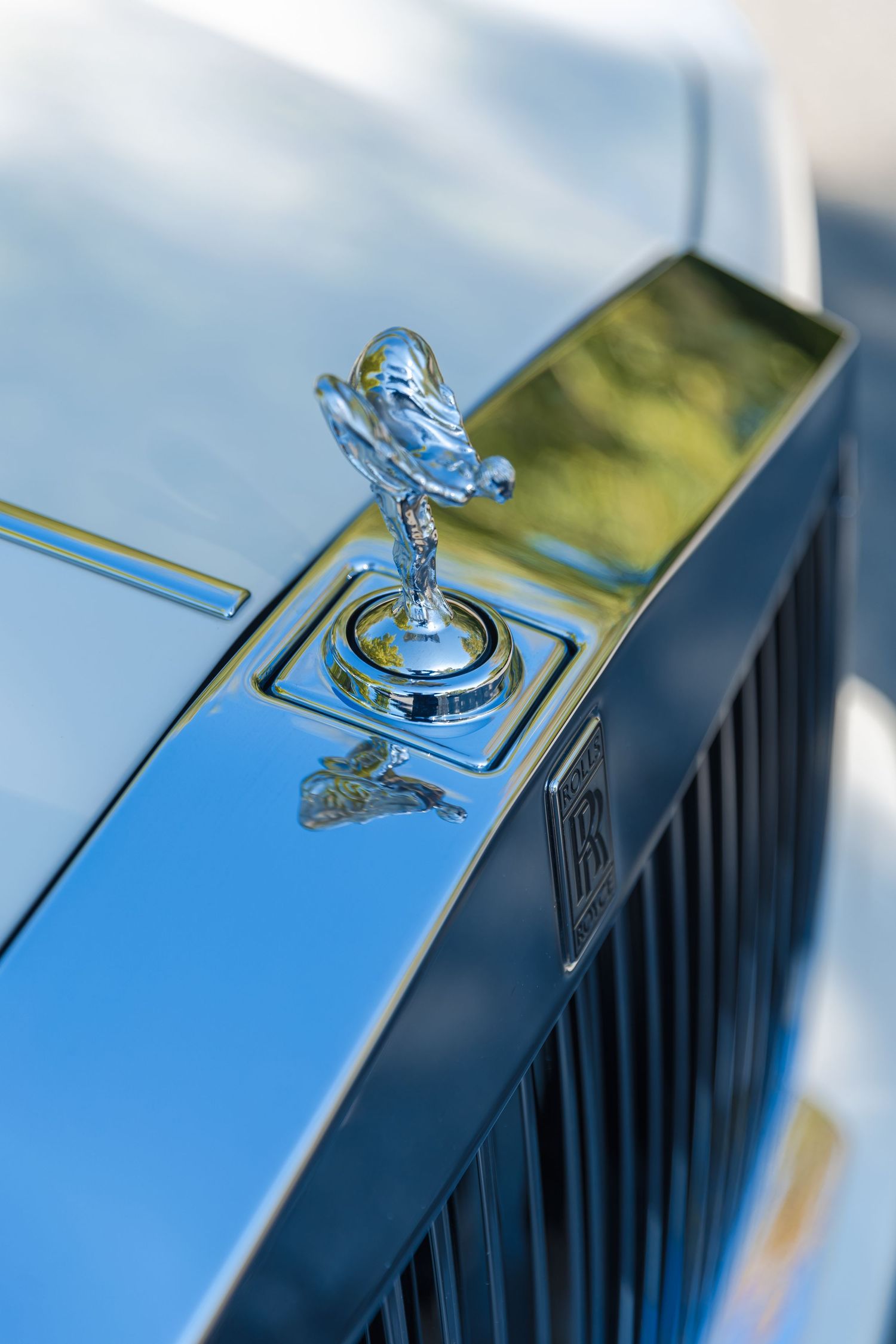 Detail shots of Rolls Royce Spirit of Ecstasy hood ornament against blue sky.
