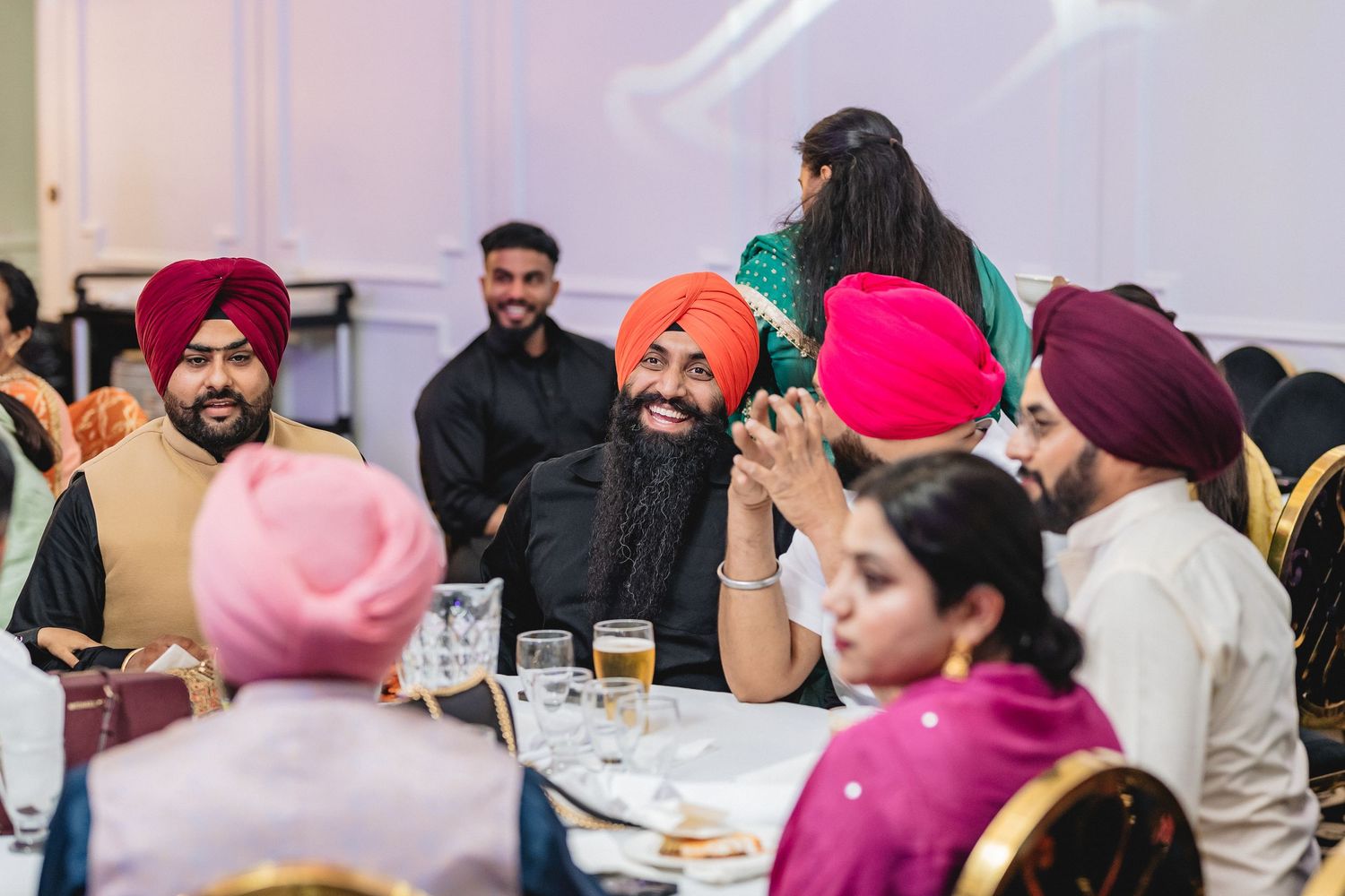 A diverse group of people enjoying a meal together at a community gathering with traditional attire.