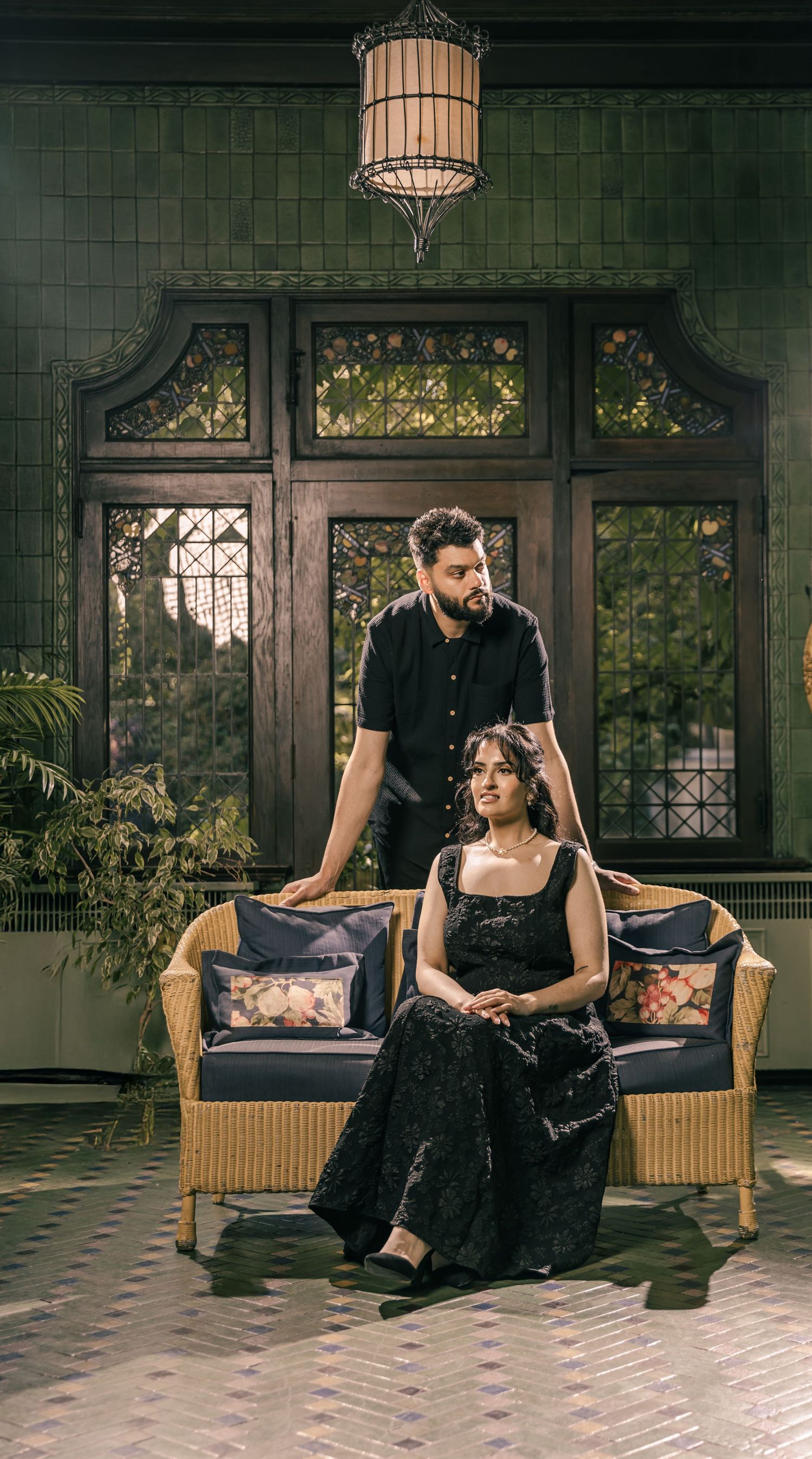 An intimate portrait session on a rattan couch in a sunlit conservatory room.