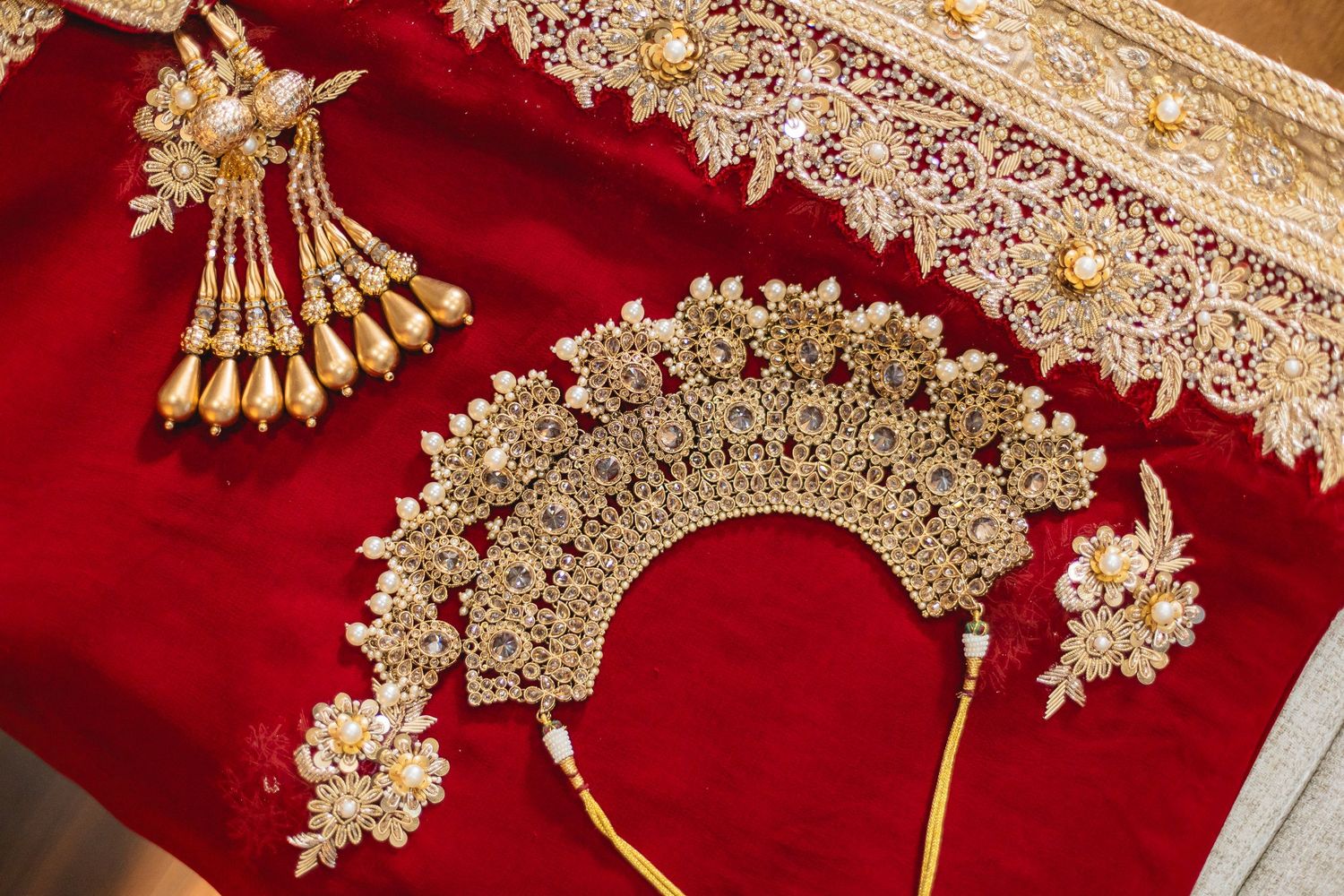 Close-up of ornate gold jewelry pieces displayed on red velvet fabric.