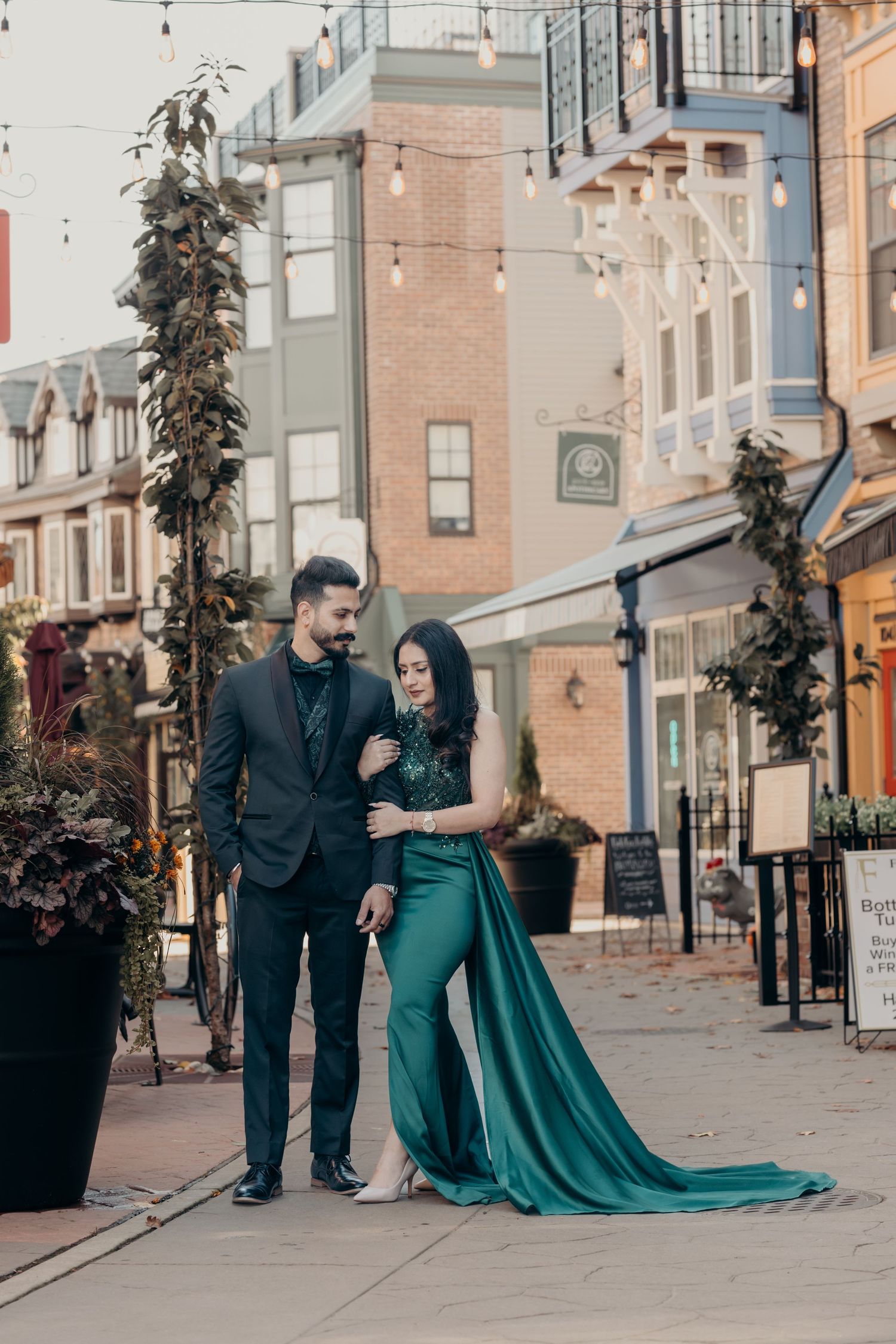 Elegant couple photoshoot on urban street with flowing emerald green dress.