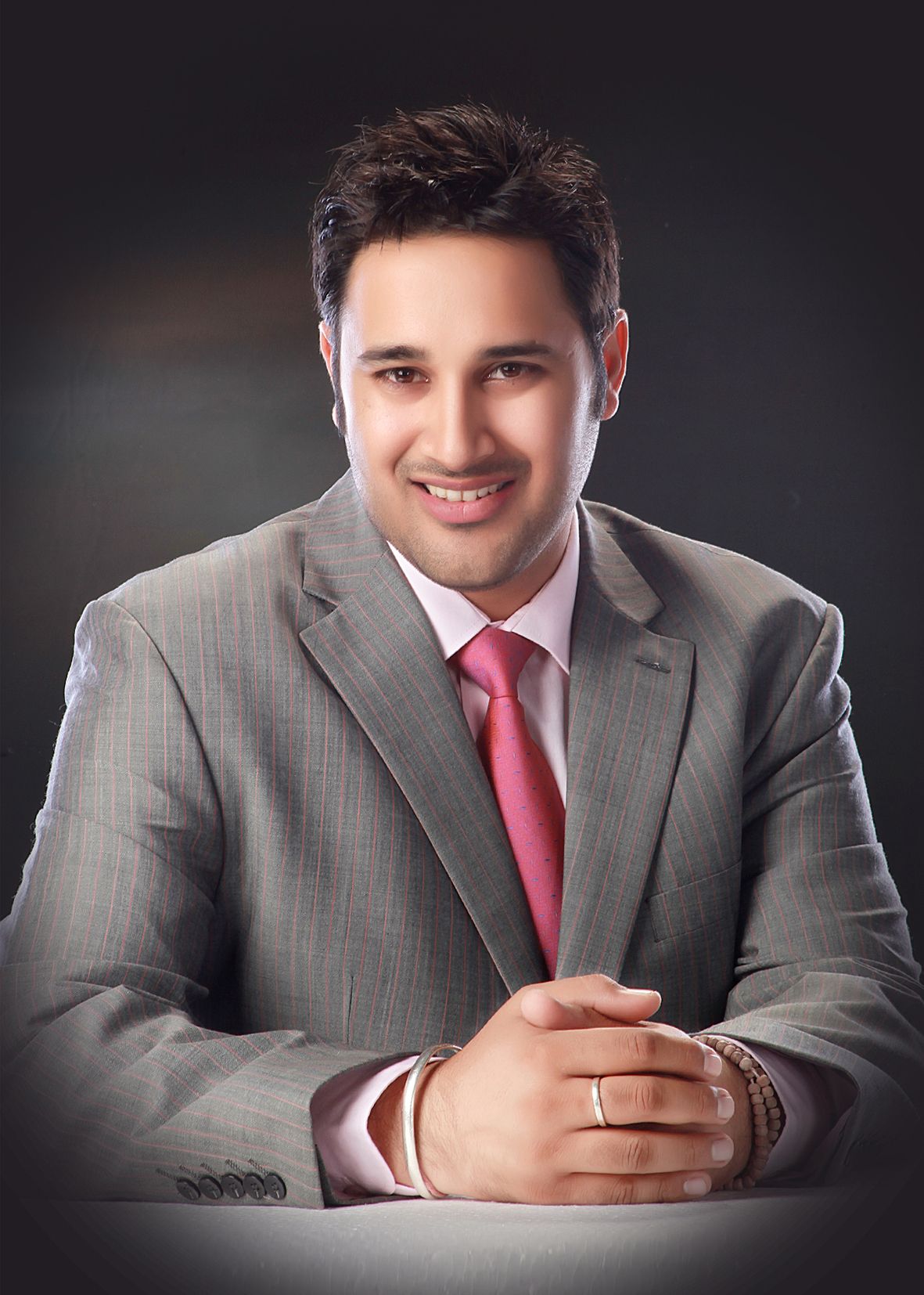 Professional headshots of a man in a grey suit and red tie against dark background.