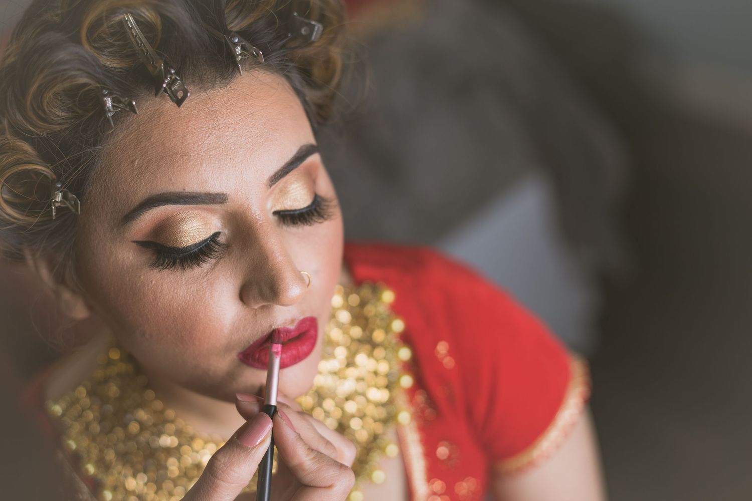 Close-up shot showcasing glamorous gold and red bridal makeup.