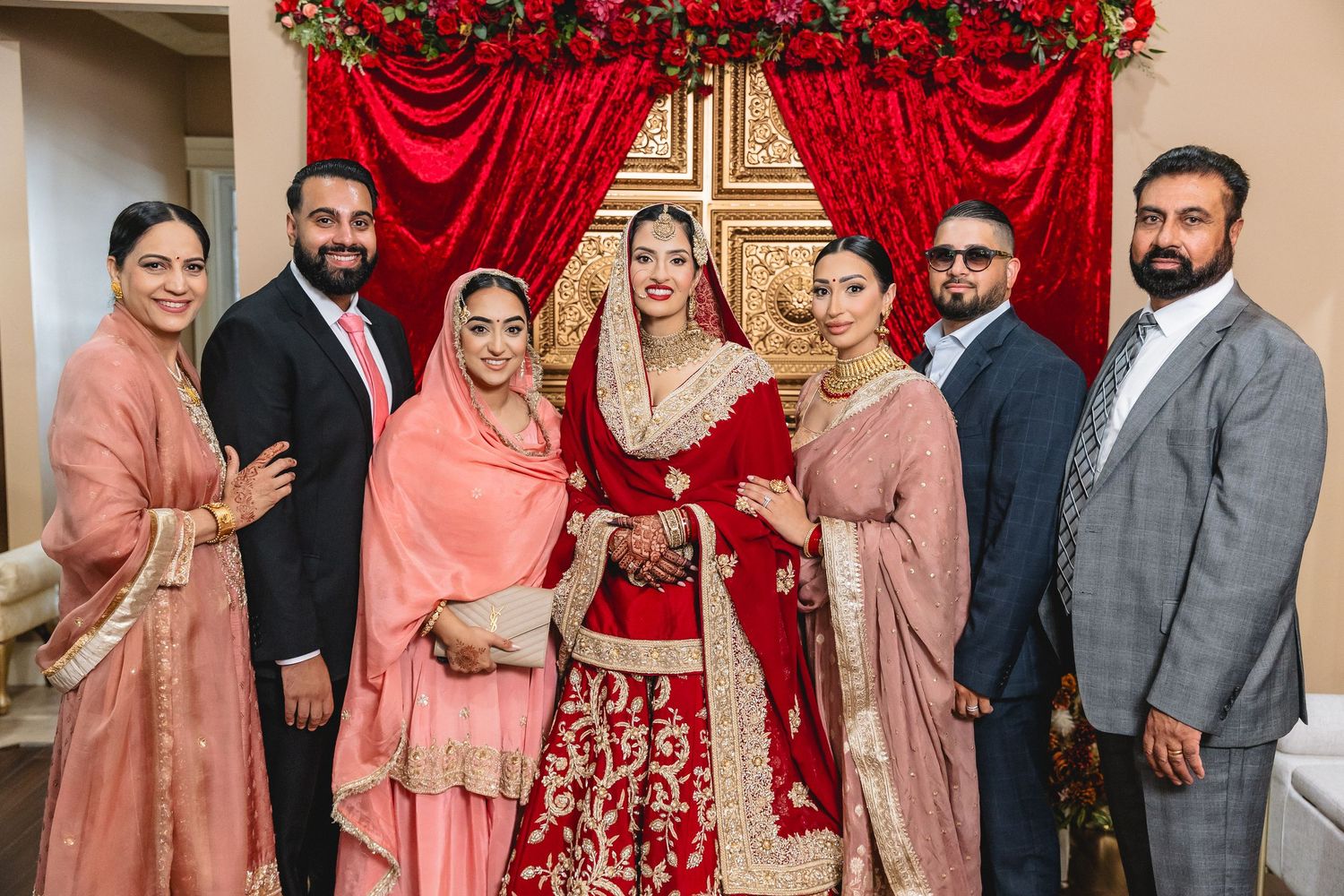 Wedding party members in coordinated formal attire posing against decorative backdrop.