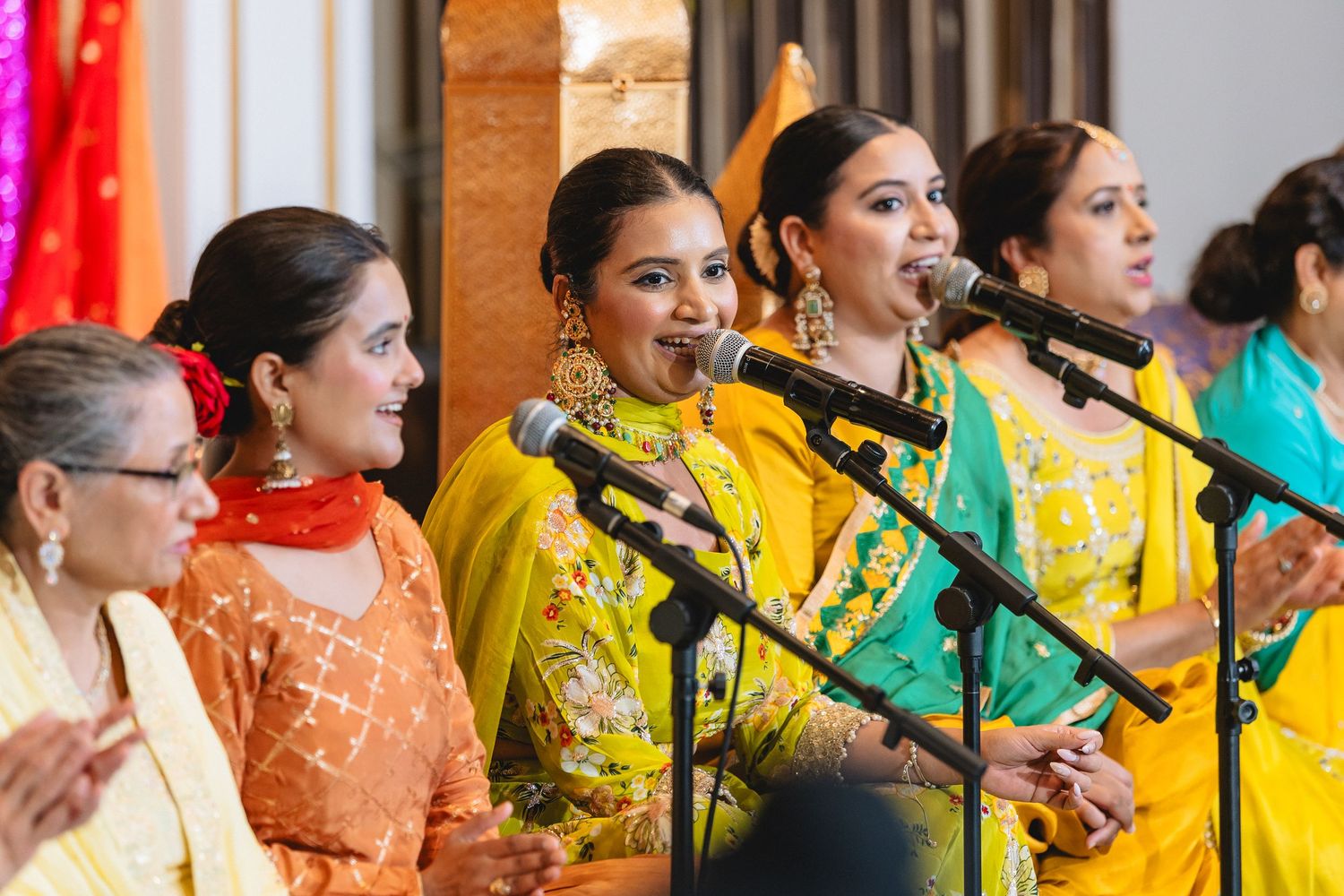 A group of women in colorful traditional Indian attire perform together at a cultural event.