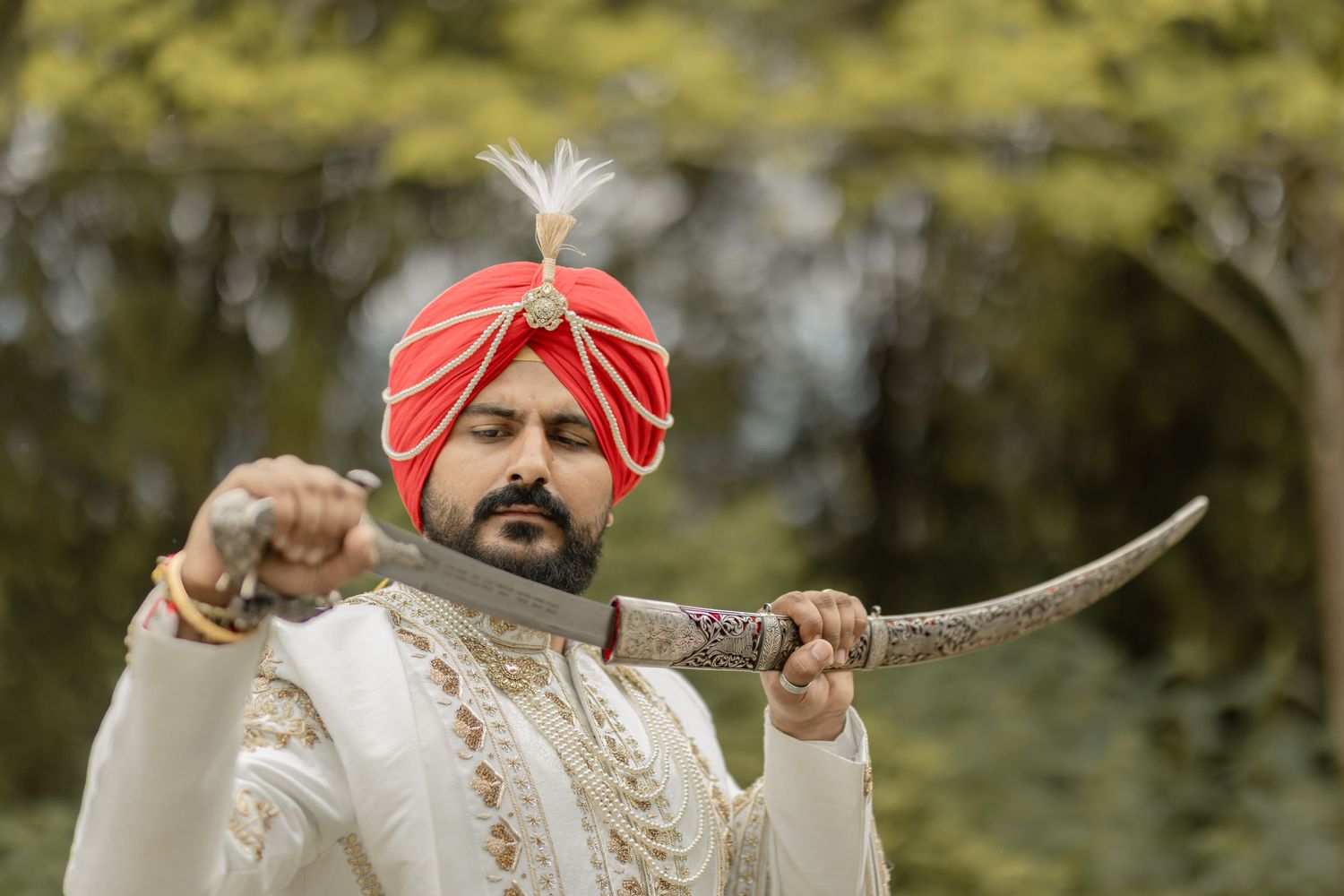 Traditional Indian wedding attire featuring ornate white and red outfits against a natural outdoor setting.