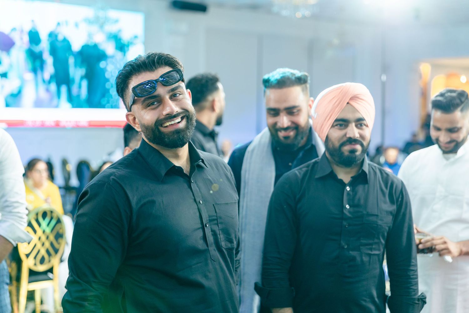 A group of guests in formal attire gather at what appears to be a cultural celebration.