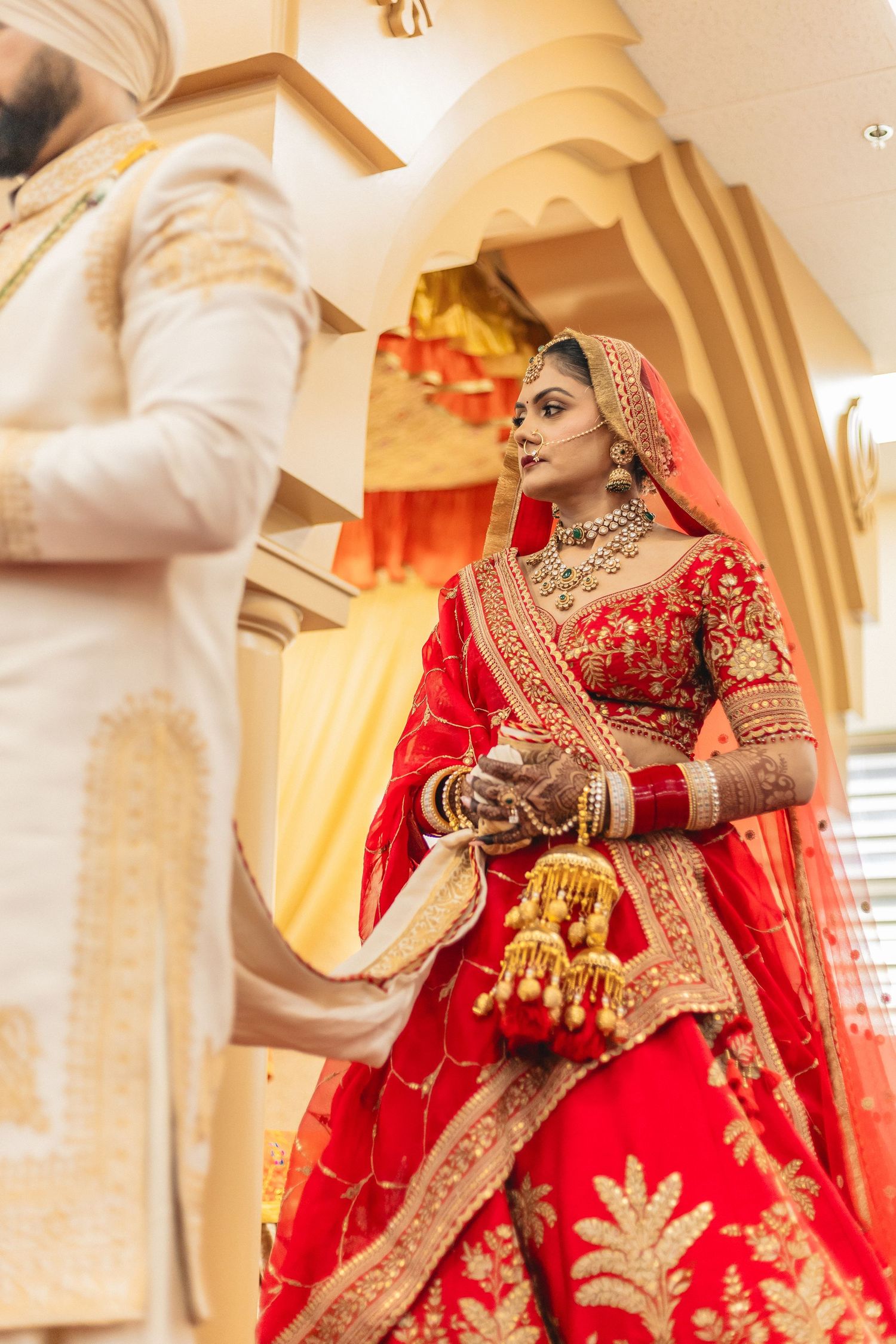 Stunning red and gold bridal lehenga with intricate embroidery details captured in an elegant venue.