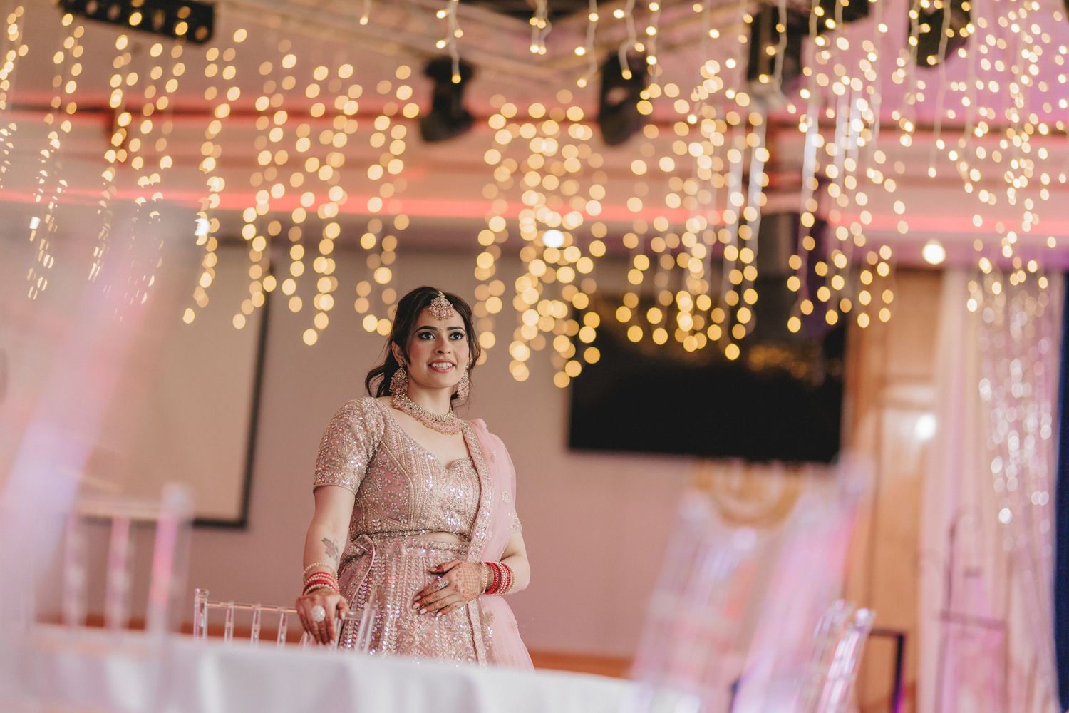 An elegant wedding venue decorated with twinkling fairy lights and pink ambient lighting. Engagement Ceremony Photoshoot