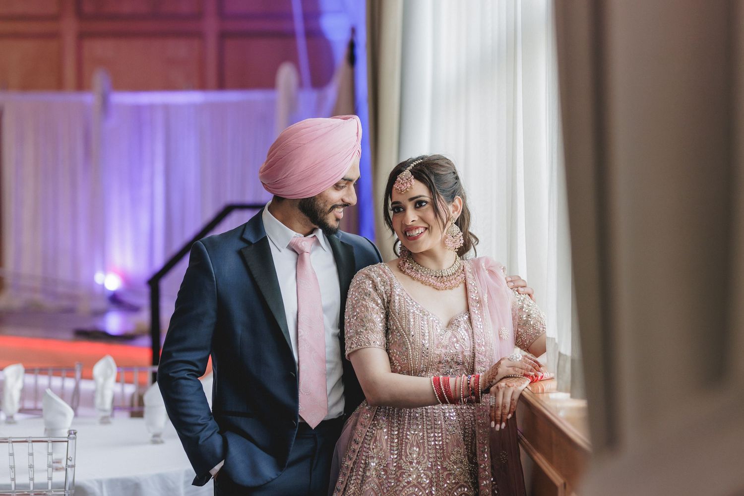 Elegant indoor celebration with purple lighting and formal attire.