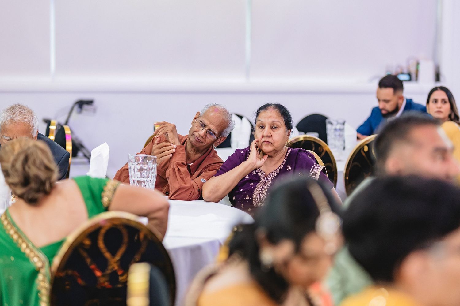 Wedding guests seated under white tent during outdoor celebration event.