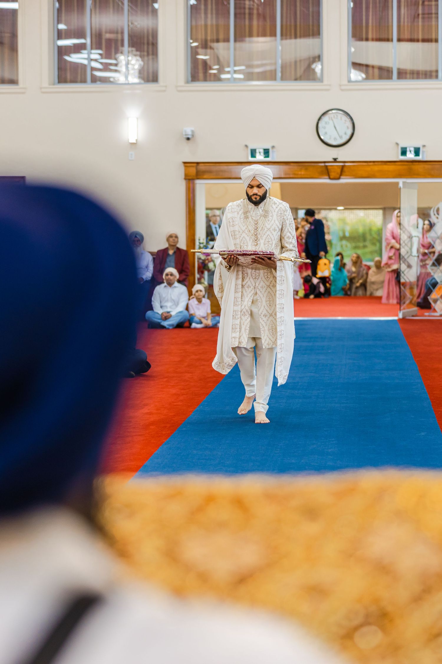 Martial arts practitioners in white uniforms practicing on red and blue mats in a bright indoor studio.