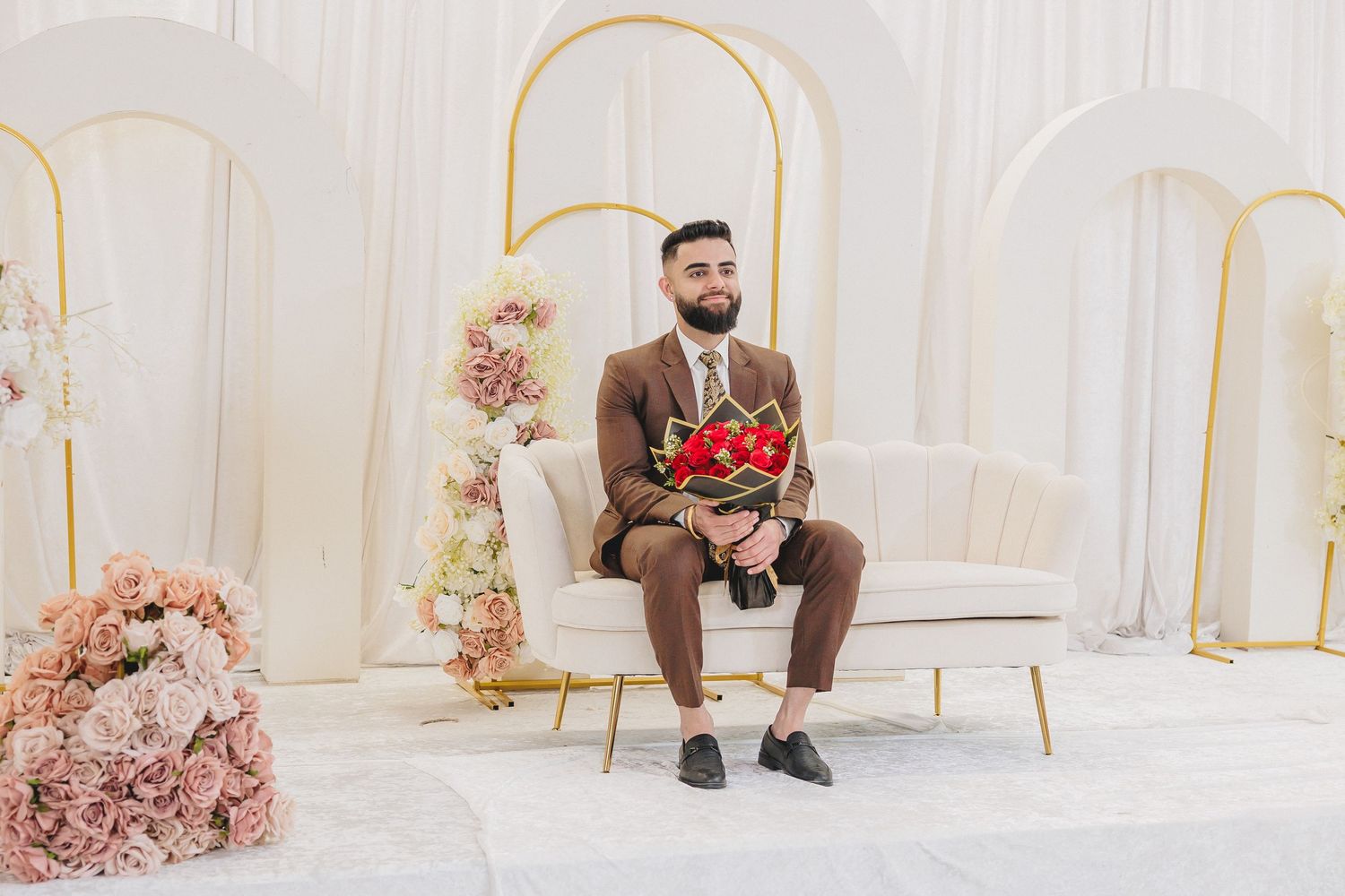Elegant white and gold themed indoor venue setup with decorative floral arrangements.