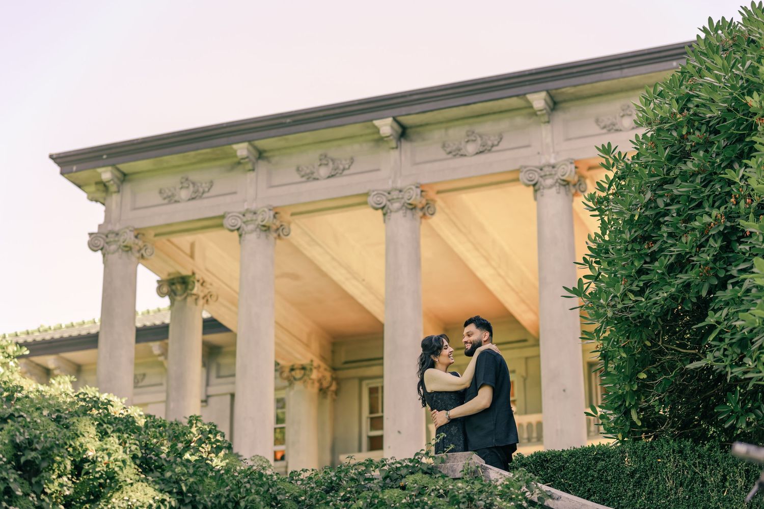 A dramatic architectural photoshoot featuring a couple among classical white columns.