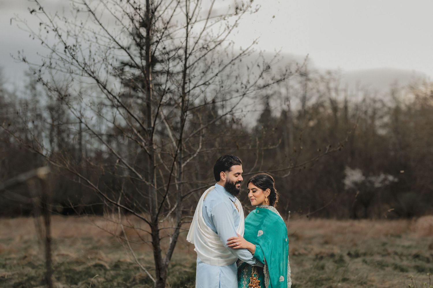 A romantic outdoor photoshoot in a natural setting with blooming trees and soft lighting.