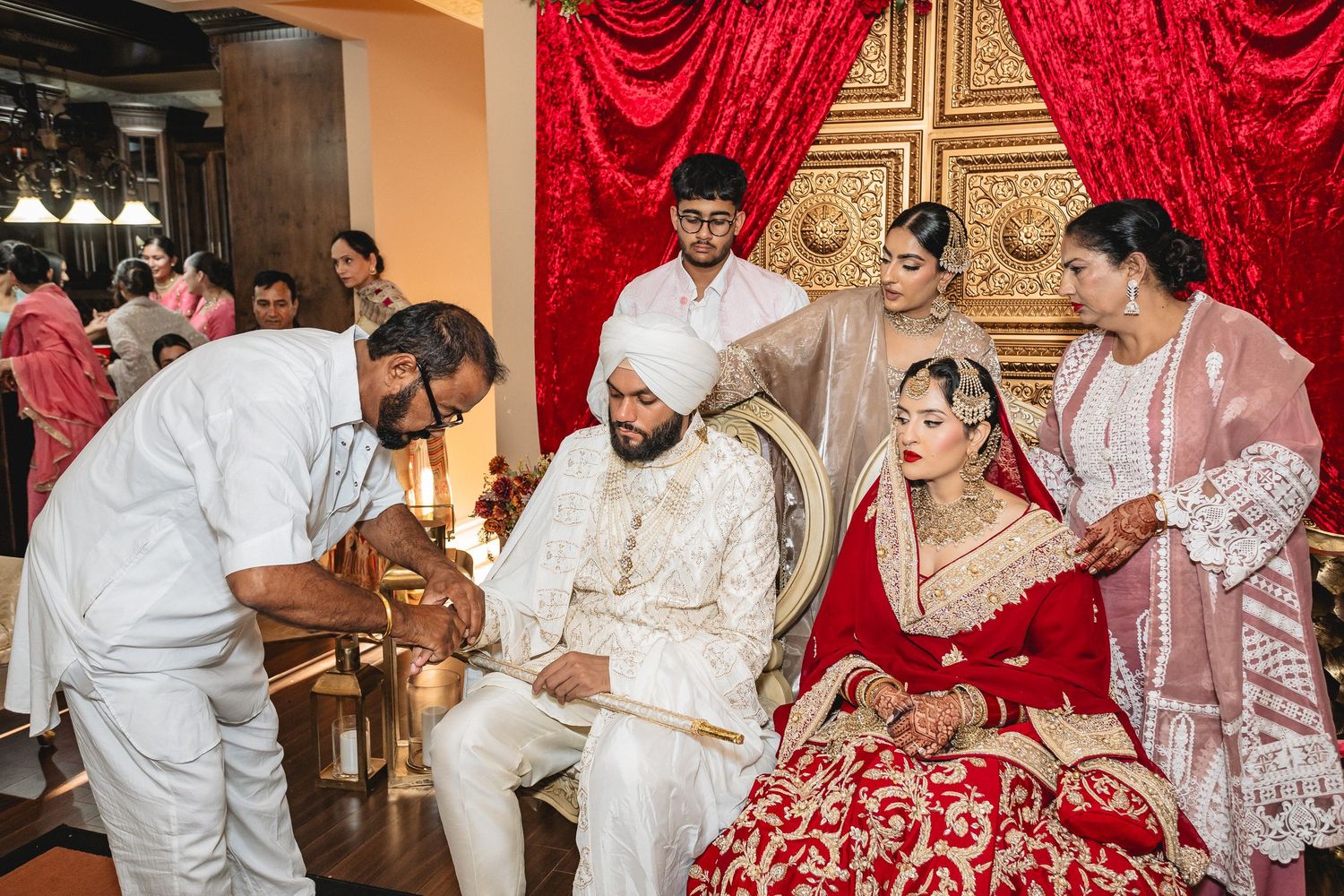 Traditional Indian wedding ceremony with guests performing customs in decorated venue.