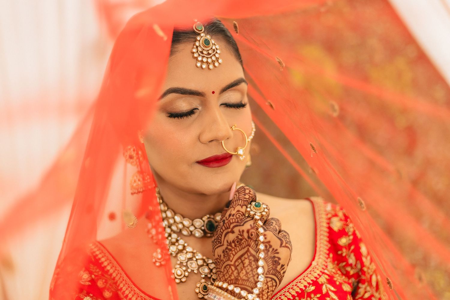 Close-up details of traditional Indian bridal jewelry and makeup in warm tones.