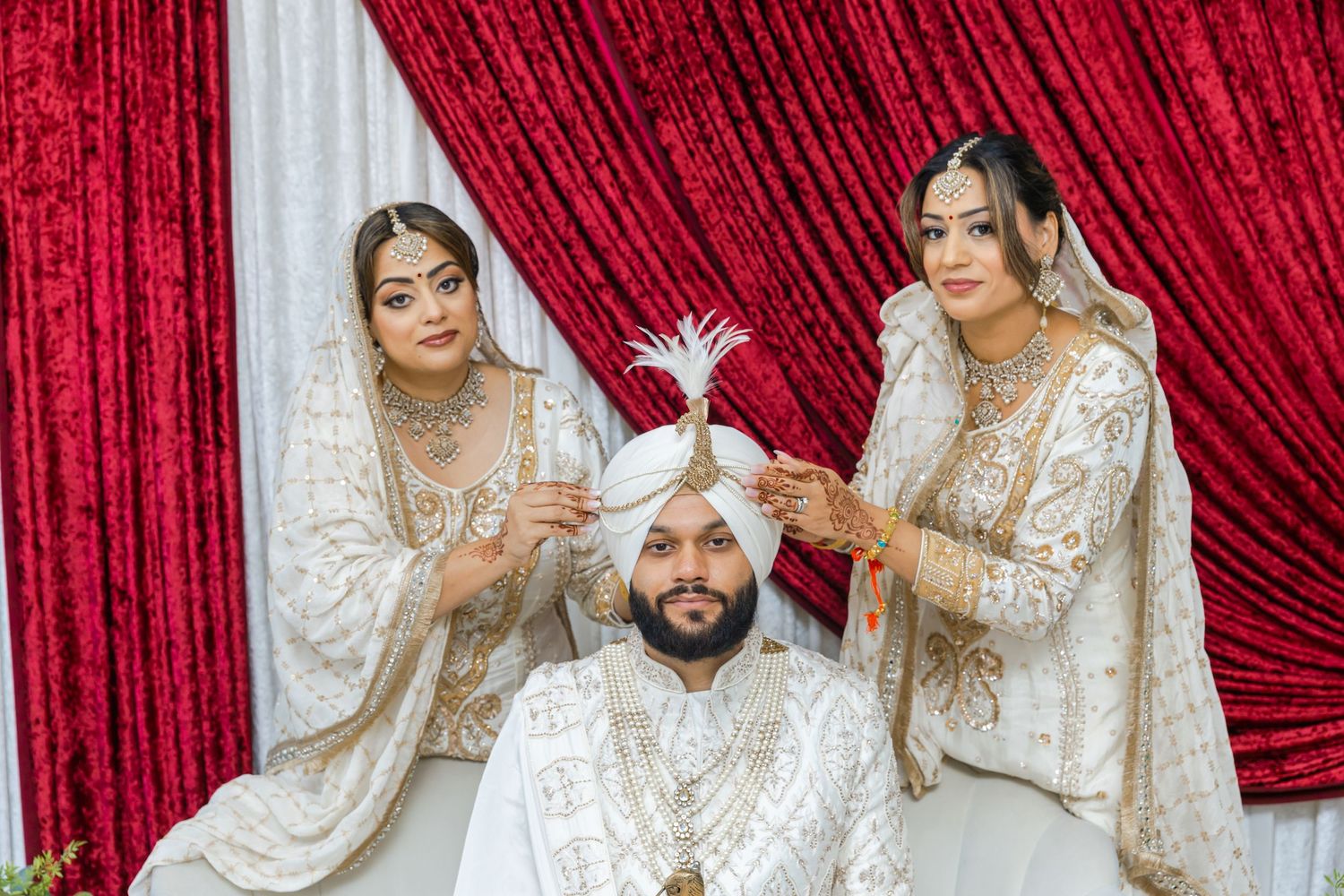 Traditional Sikh wedding ceremony moments captured against red curtain backdrop.