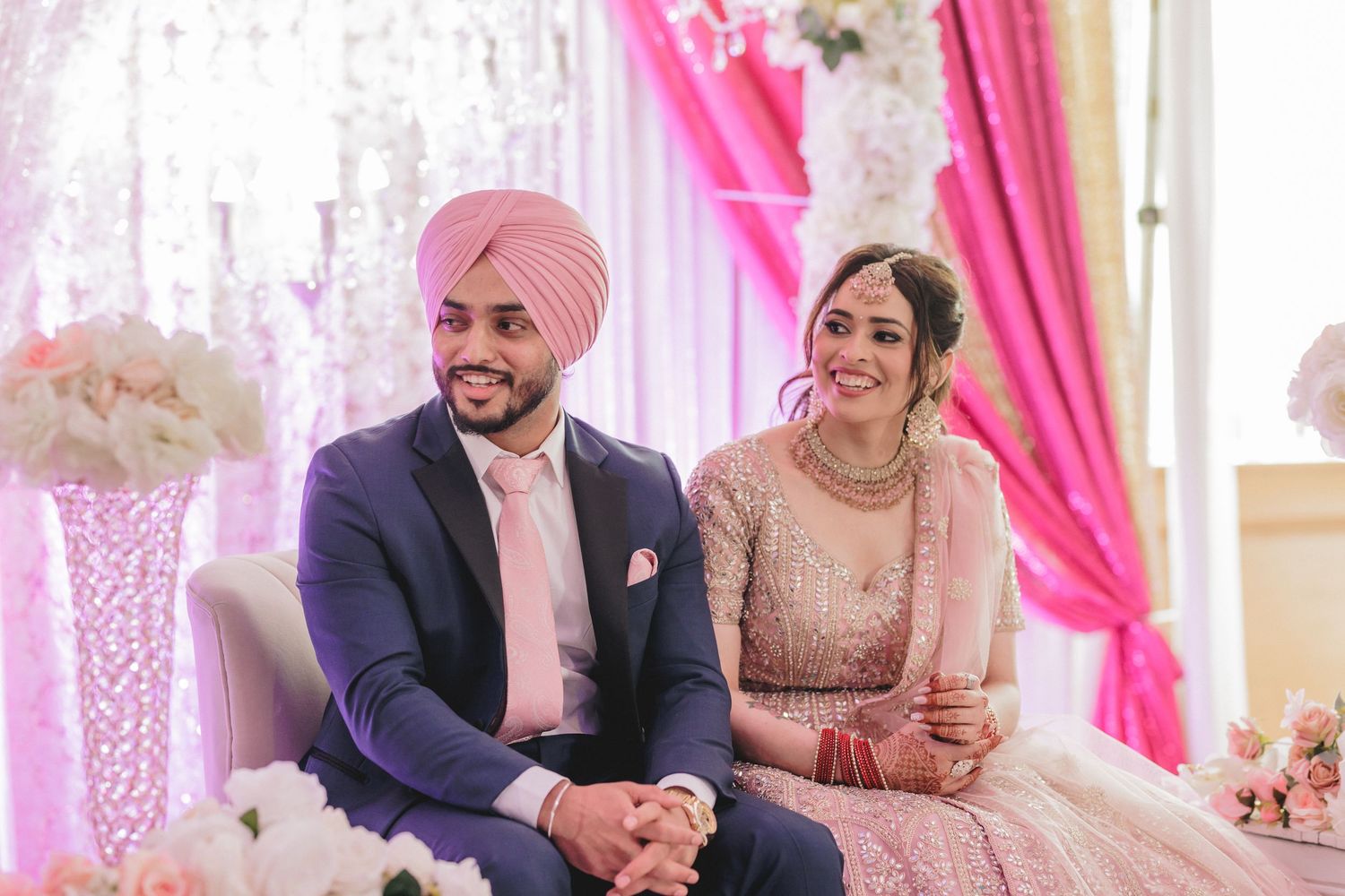 Wedding ceremony space decorated in pink and white with elegant lighting and traditional elements.