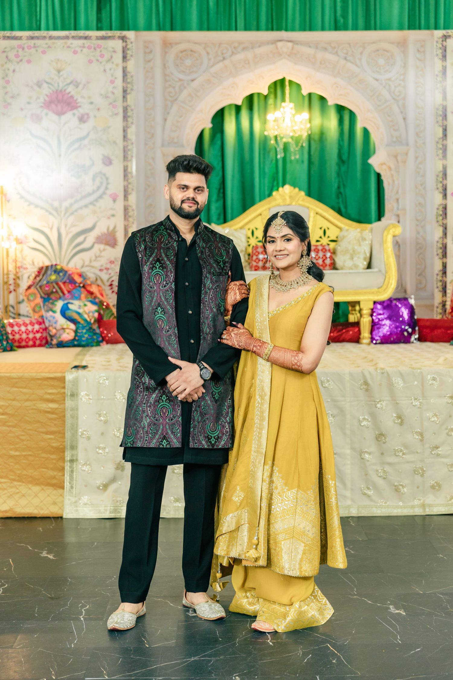 Performance scene with gold and black outfits against green curtains and decorative backdrop.