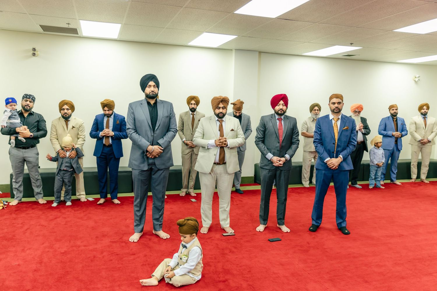 Panoramic view of wedding guests standing along walls during traditional Sikh ceremony.