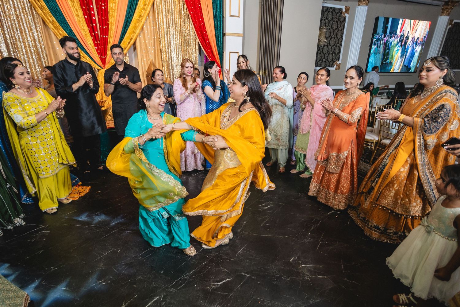 Panoramic view of an indoor venue decorated with gold curtains and colorful traditional decor for a celebration.