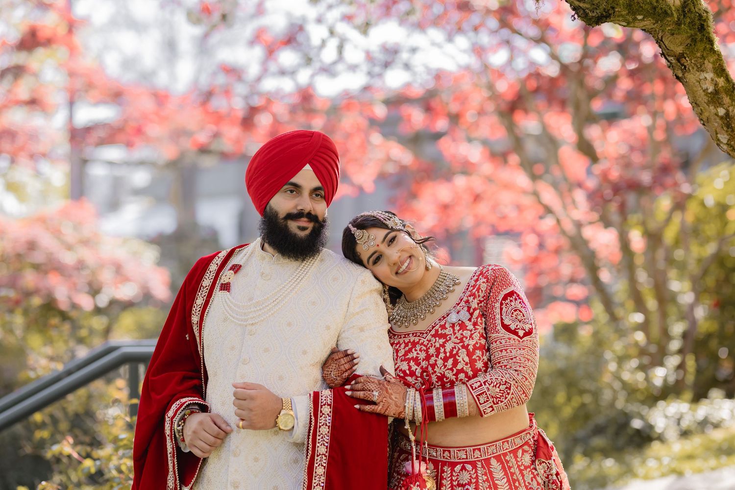 Spring cherry blossoms frame a romantic cultural wedding photoshoot with red and white traditional attire.