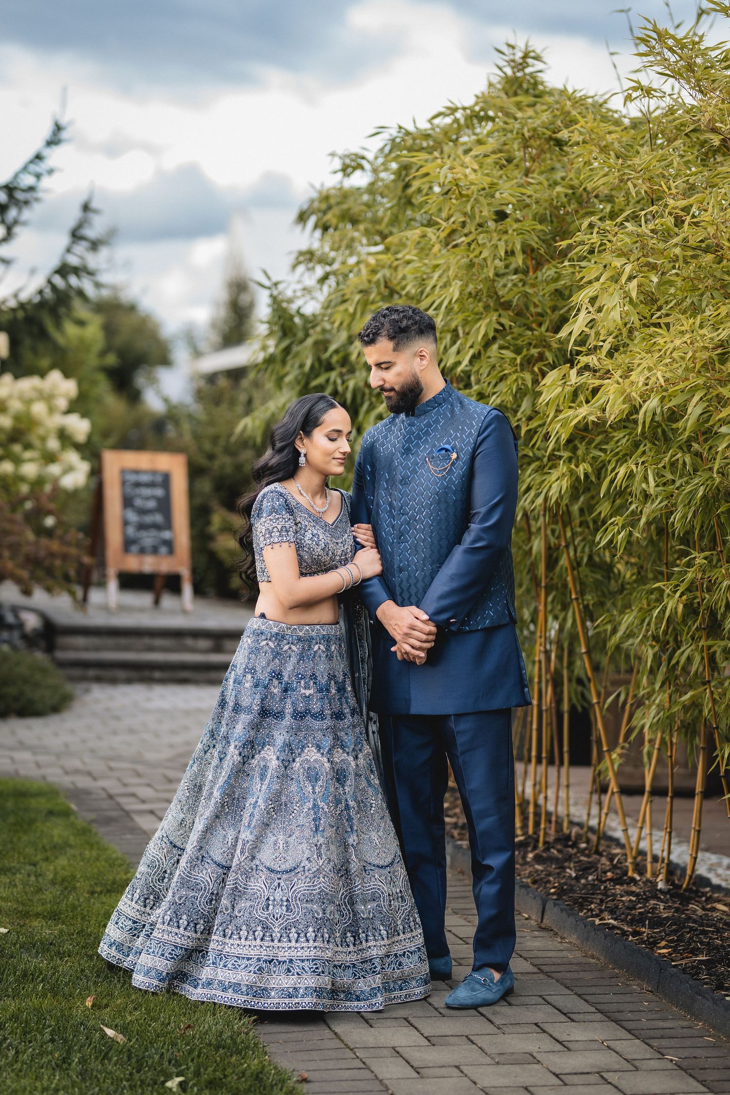 Romantic outdoor portraits of couple in blue attire against bamboo backdrop.